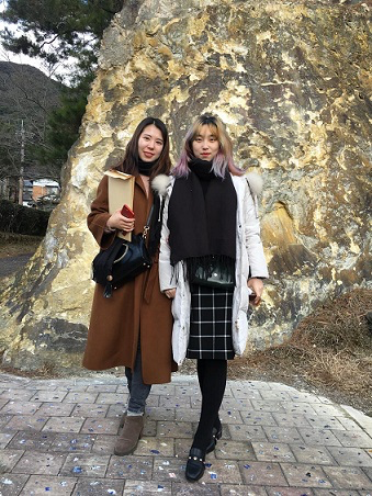 Two women standing in front of a rock wall Description automatically generated with low confidence
